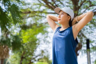 Asian woman warming up before running in the morning in the park