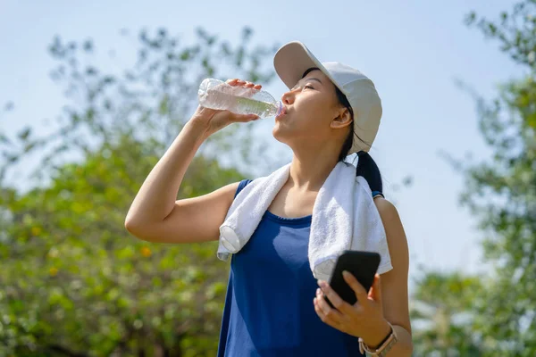 Young beautiful asian drinking water after jogging running outdoor. Sport healthy running concept.