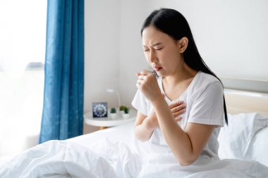 Pijamalı güzel Asyalı kız hasta ve öksürüyor..