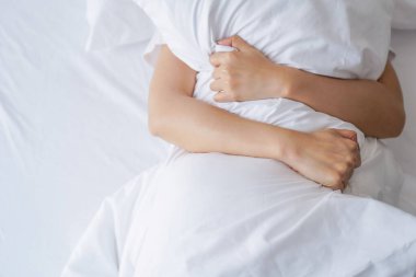 Genç ve seksi bir kadının beyaz yatakta orgazm olduğunu gösteren bir manzara. Reklam için seks ve erotik kavram