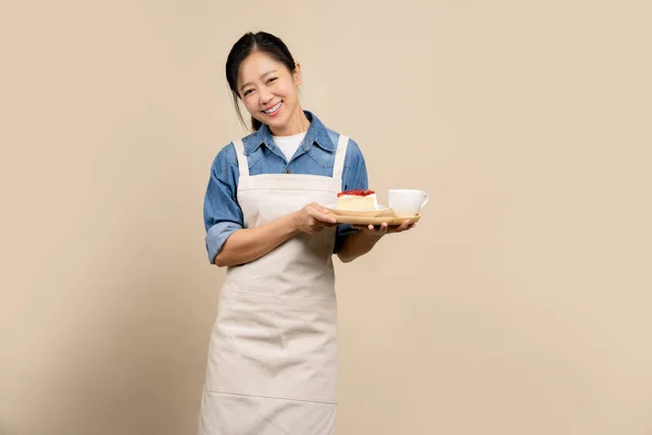 배경에 앞치마를 아시아 웨이트리스 쟁반에 케이크와 음료를 행복하게 — 스톡 사진