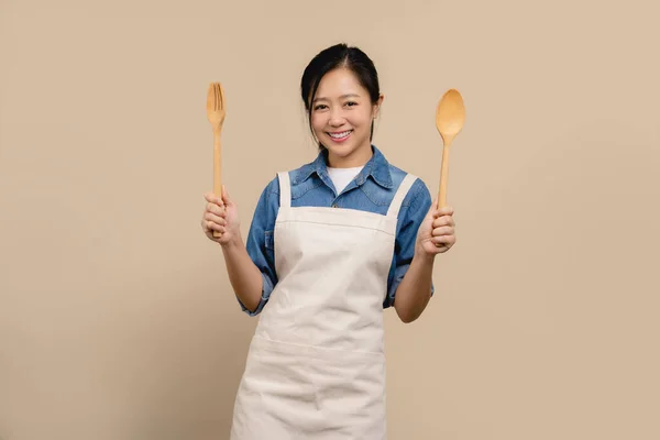 Ritratto Donna Asiatica Allegra Indossando Grembiule Tenendo Cucchiaio Forchetta Sfondo — Foto Stock