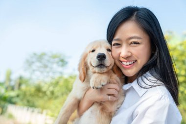 Güzel Asyalı genç bir kadın, köpeğini kucağında tutuyor. Kol gülüşü ve mutluluğunda Golden Retriever cinsi var. Aşk hayvanları konsepti.