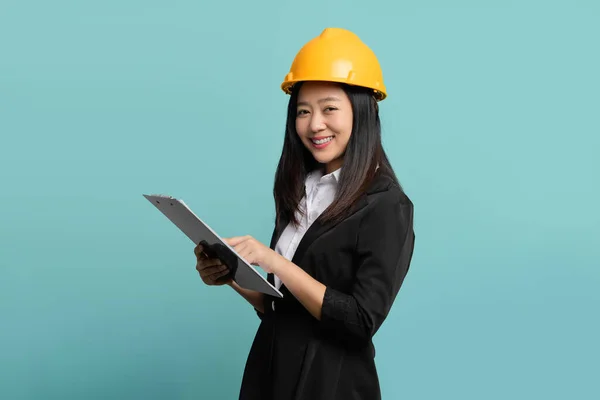 stock image Young female engineer using a clipboard isolated on green background