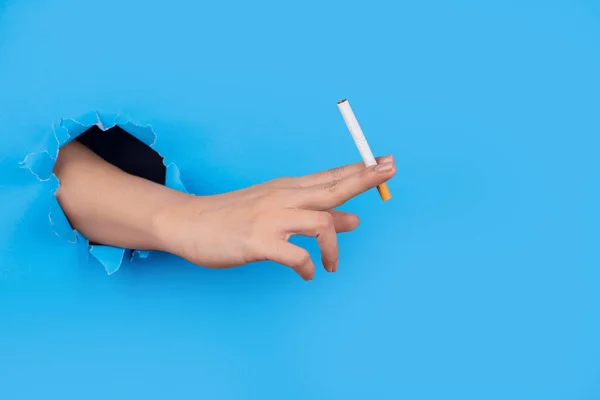 Ruka Přes Papír Drží Cigaretu Modrém Pozadí — Stock fotografie