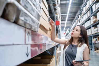 Genç bayan yönetici depodaki paket kutularını kontrol ediyor. Lojistik ihracat konsepti.