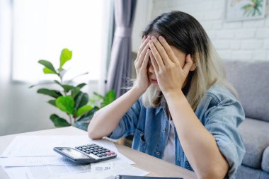 Finansal borcu olan Asyalı kadın, evde hesaplanan masraflar yüzünden eli kolları bağlı oturuyor.