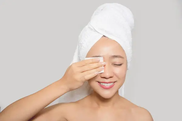 Happy asian woman using cotton pad clean make up on her face