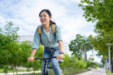 Şehir parkında bisiklet süren güzel Asyalı kadın.