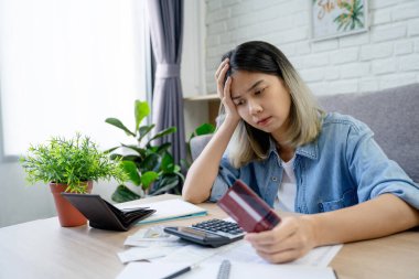 Finansal borcu olan, kredi kartı tutan stresli Asyalı kadın fatura masraflarını hesaplıyor..