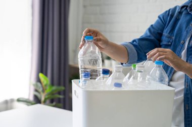 Bir kadın geri dönüşümlü plastik şişeleri toplayıp evdeki çöp kutularına ayırıyor..