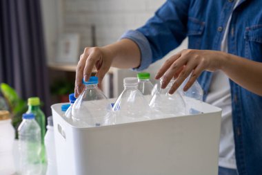 Geri dönüşümlü plastik şişeleri evdeki çöp kutusuna sıralayan kadın.