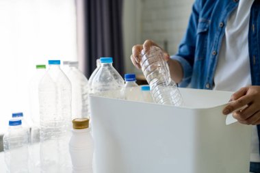 Kullanılmış plastik şişeyi evdeki çöp kutusuna atan kadın.