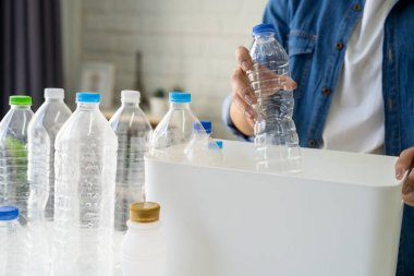 Geri dönüşüm için çöpleri ayıran Asyalı kadın. Plastik şişeleri geri dönüşüm kutusuna koydu..