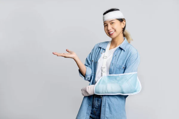 Broken arm,  happy young asian woman wearing soft splint due to sore arm.