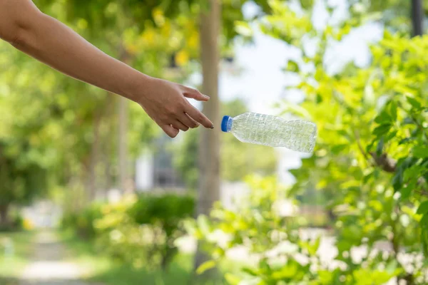 Photo of hands throwing away plastic bottles in nature.