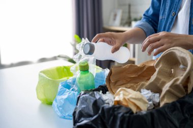 Kadın kullanılmış plastik şişeleri evdeki çöp kutusuna koyuyor. Atık geri dönüşümü.