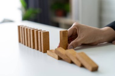 Yöneticinin elleri yıkılan dominoları tamamen çökmesini önlemek ve istikrarı sağlamak için durduruyor..