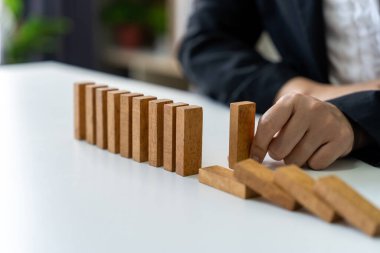 İş hayatında riskler ve stratejiler. İş kadını masadaki domino taşlarını durdurmaya çalışıyor..