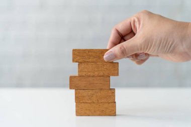 Genç iş kadını, risk stratejisi planı için tahta blokları beyaz masaya yerleştiriyor. iş kavramı.