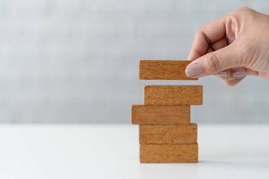 Eller, strateji planı için beyaz masaya tahta bloklar yerleştiriyor. risk kavramı.