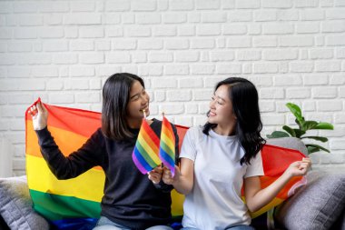 Gökkuşağı LGBTQ bayrakları taşıyan güzel Asyalı lezbiyen çift, eşitlik, homoseksüellik ve ayrımcılığı destekliyor