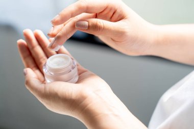 Kadın ellerine krem sürüyor. 