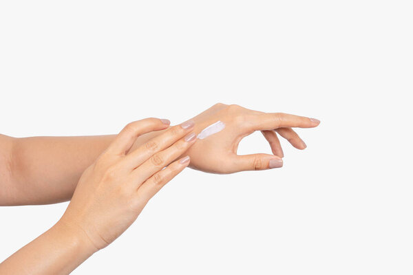 Health and beauty care of young Asian woman using her fingers to apply moisturizing cream to the back of her hands, body cream