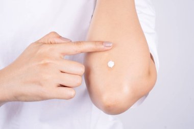 Dirseklerini tımar eden ve cilt kremi süren bir kadın.