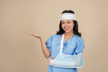 Asyalı kadın hasta, kolundan yaralandığı ve başından yaralandığı için alçı takıyor. Kişisel kaza ve sigorta konsepti.