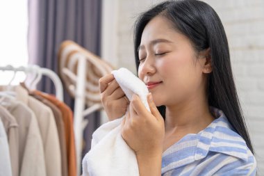 Güzel Asyalı ev hanımı, çamaşır yıkadıktan sonra ev hanımı konseptini kokluyor.