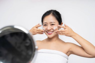 Bir kadın makyajdan önce nemlendirici sürüyor.