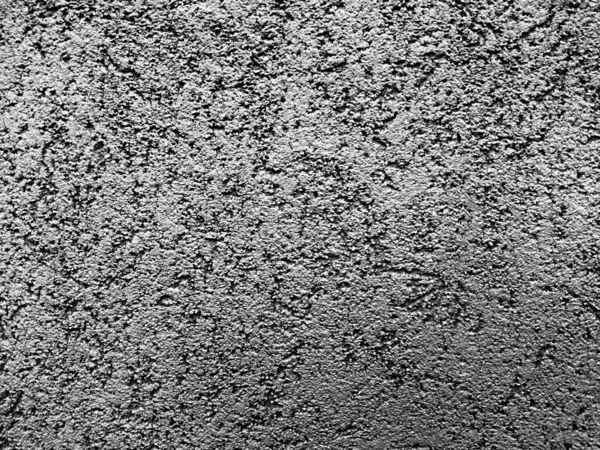 Relief abstract drawing on a wall covered with decorative plaster. Gray background, monochrome photo.