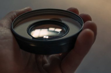 Photographic filter in hand reflecting light.