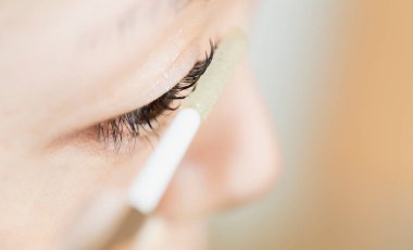 Bir kişi dikkatlice göz kapağına siyah göz kalemi sürüyor..