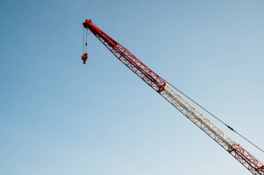 Gökyüzü arkaplanı boyunca çapraz uzanan uzun vinç kolu.