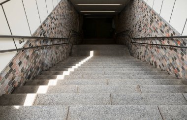 Güneşli merdivenler fayanslı bir yeraltı geçidine iniyor..