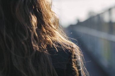 Açık havada gün ışığında parlayan uzun kahverengi saçlı yakın plan.
