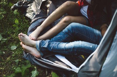 Kamp gezisi sırasında çimenlerin üzerinde çıplak ayakla oturan çift.