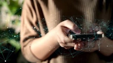 Genç bir kadının eli akıllı telefonu kullanarak sosyal medya alışverişi yapıyor, haberleri kontrol ediyor, mobil oyunlar oynuyor ya da oturma odasında bağlantı ağını gösteren grafiklerle mesajlaşıyor..