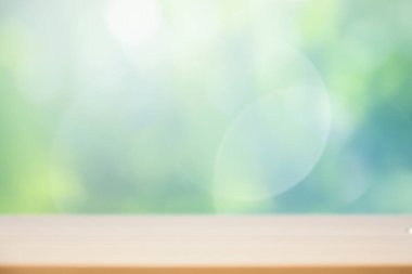 Ürün gösterimi için soyut yeşil bokeh arkaplan üzerindeki ahşap masa üstü.