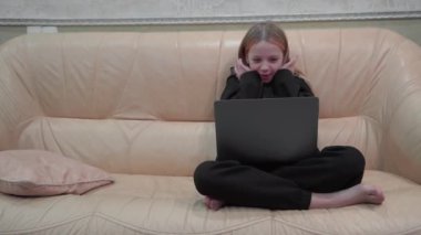 Evdeki kanepede oturan genç bir kız bilgisayarını kullanarak video bağlantısı ile konuşuyor...