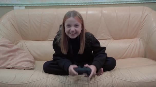 若い女の子が熱心にビデオゲームをプレイし 彼女は勝つと喜んで彼女の手を上げ 彼女は喜びの感情を表現します — ストック動画