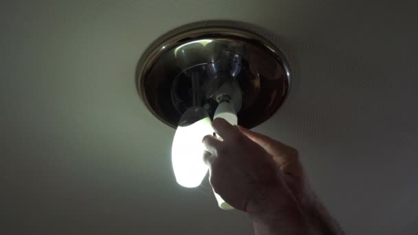 天井の小さなランプに省エネ電球をねじ込んでいます — ストック動画