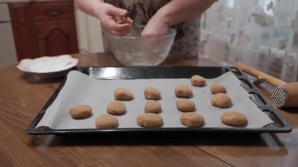 一个女人准备自制的饼干 她用羊皮纸把它们放在烤盘上 — 图库视频影像