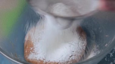 Women's hands knead the dough in a glass bowl for making homemade cookies. Close-up.