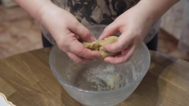 Women's hands prepare pieces of dough for baking homemade cookies.