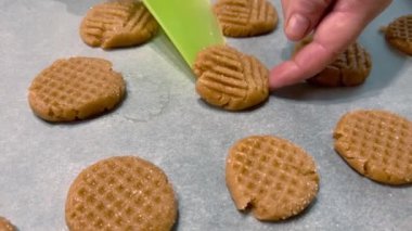 Women's hands straighten cookies lying on parchment paper before baking.