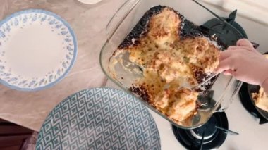 A woman is putting freshly cooked fried meat into plates.