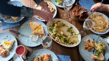 Etrafında aile üyelerinin toplandığı çeşitli lezzetli yemeklerle dolu bir yemek masası.